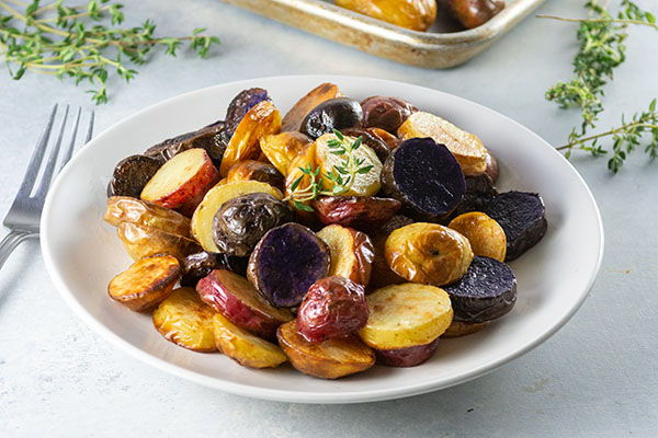 A plate of colorful roasted potatoes garnished with herbs.