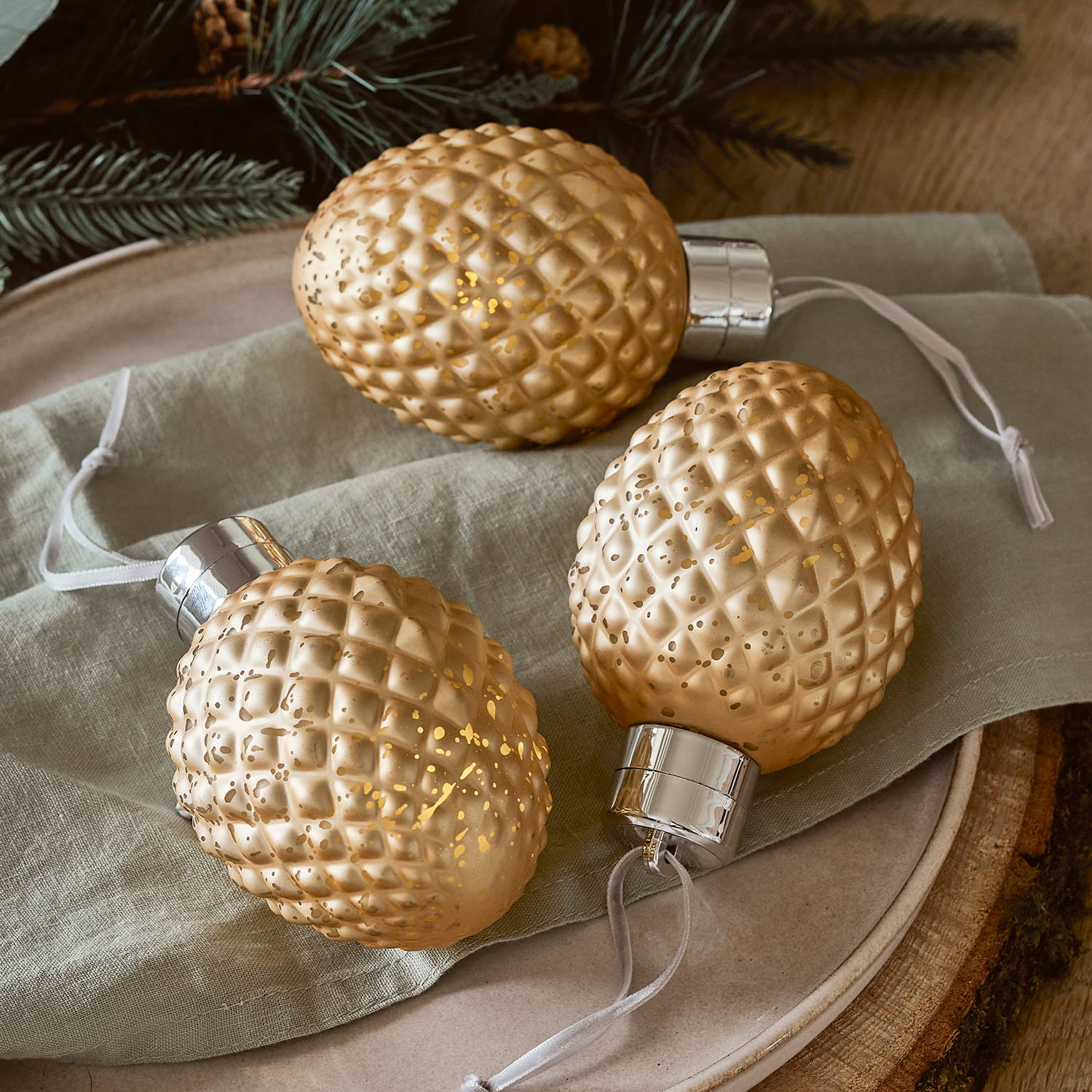 3 Gold Baubles on a wooden table.