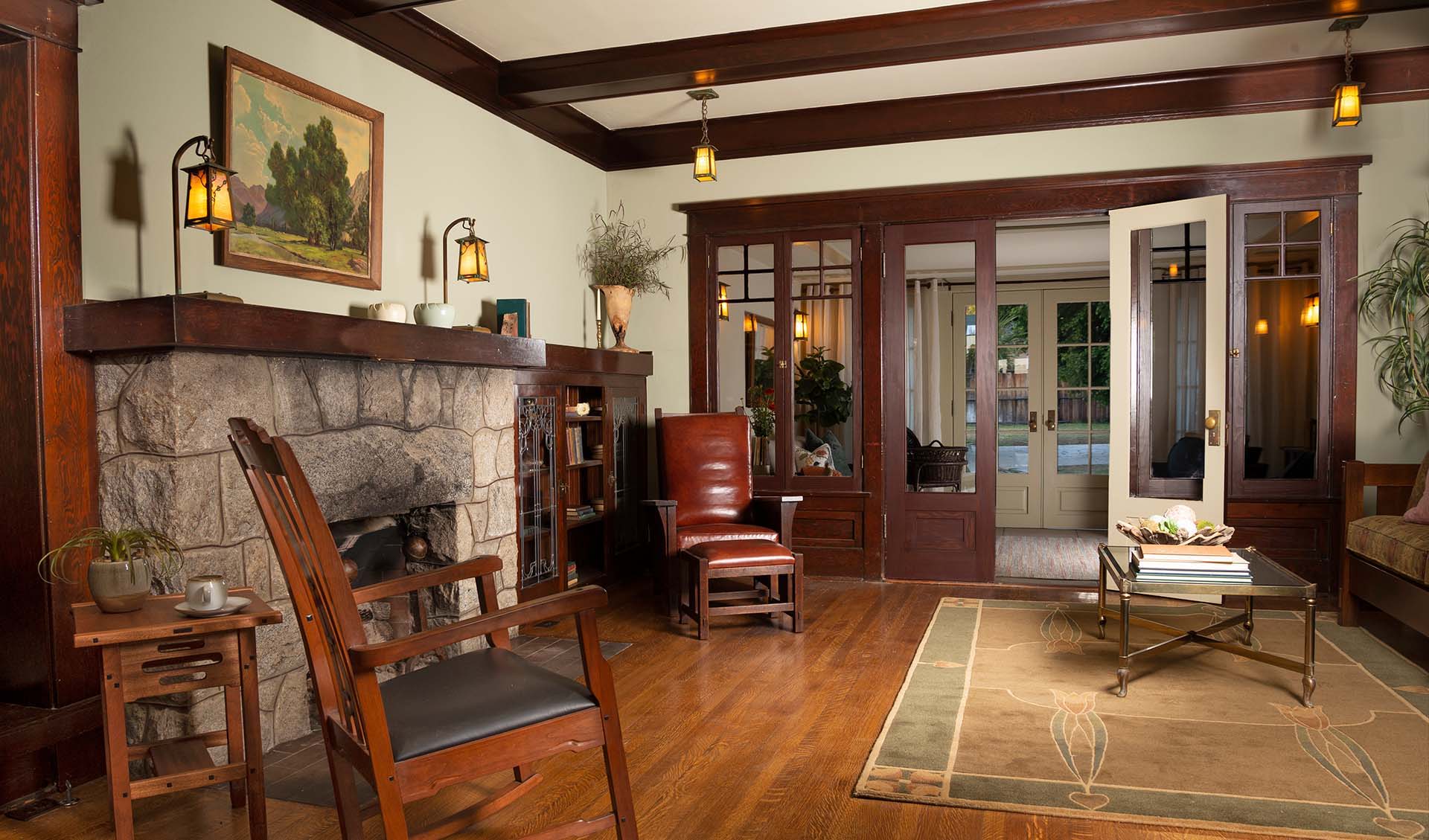 A bungalow living room with Stickley furniture and other Craftsman furnishings like rugs and lighting. It has a stone fireplace.