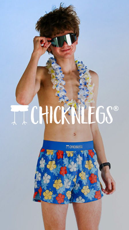 Young man in sunglasses and floral shorts, wearing a lei.