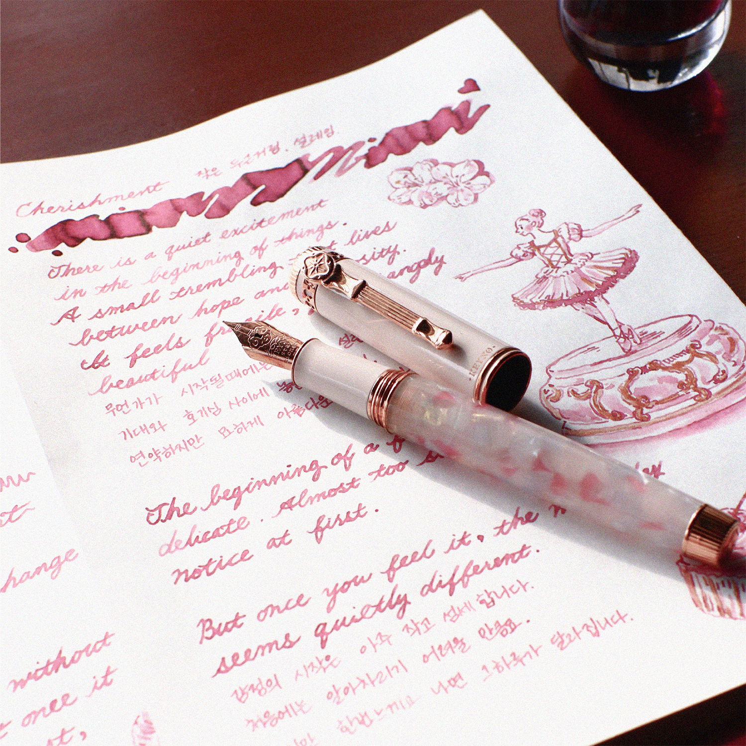 Dominant Industry Keyno Cherishment fountain pen with acrylic barrel and rose gold trims sitting atop a paper handwritten with the matching light rose ink