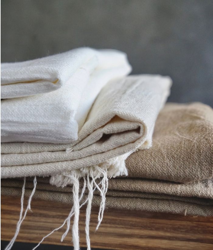 A stack of folded linen fabrics in neutral colors.