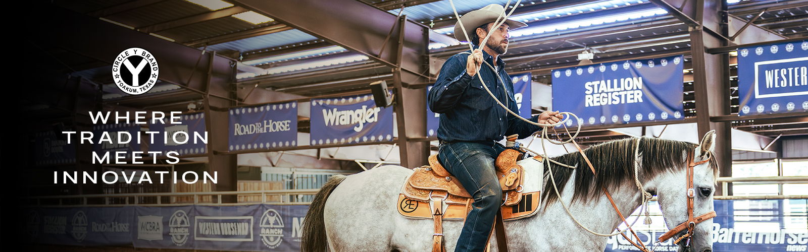 Cowboy riding a horse in an indoor arena with banners.