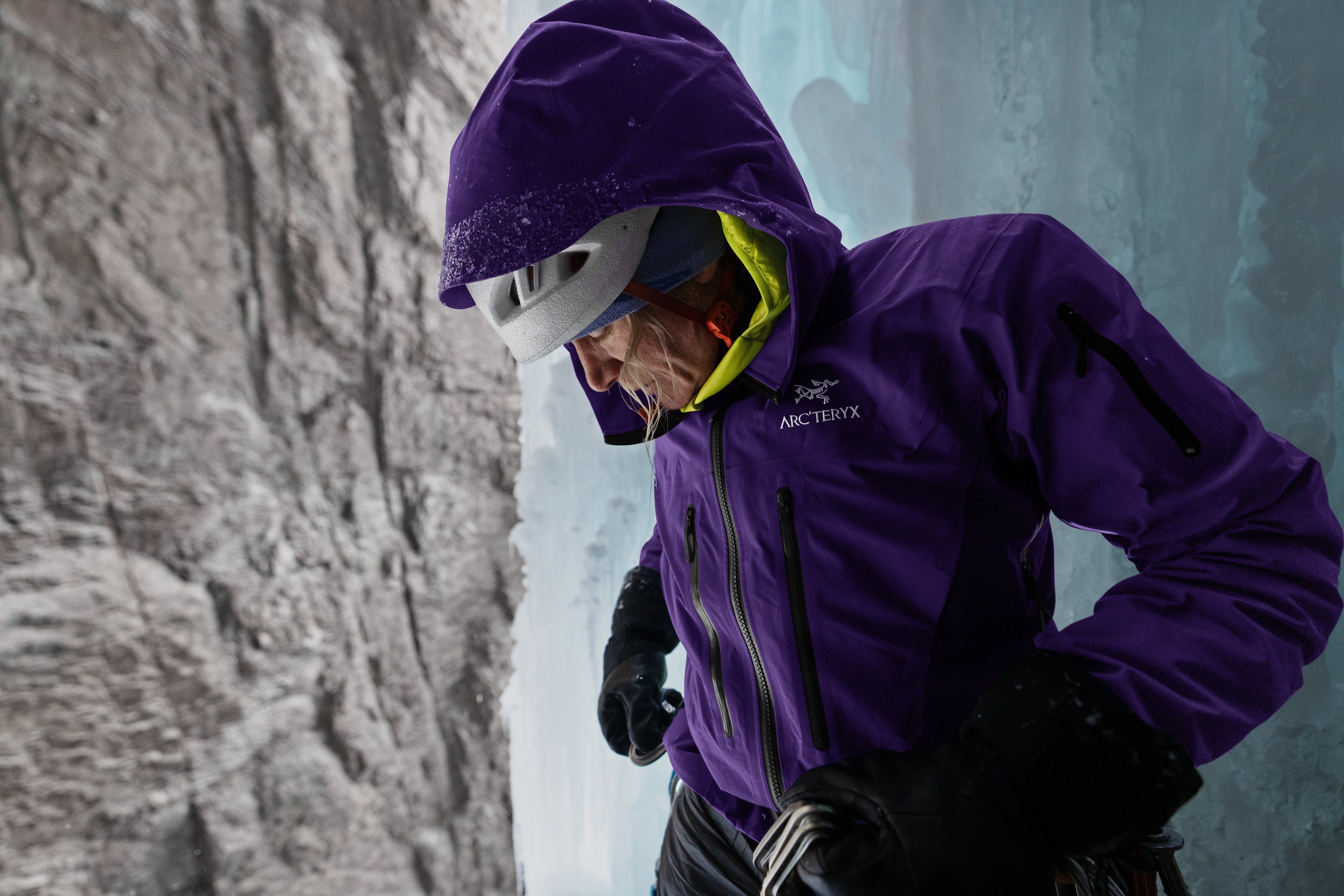 Climber in purple jacket preparing on icy terrain.