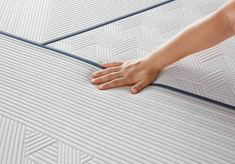 Hand touching the cooling gel-infused foam surface of a hybrid mattress