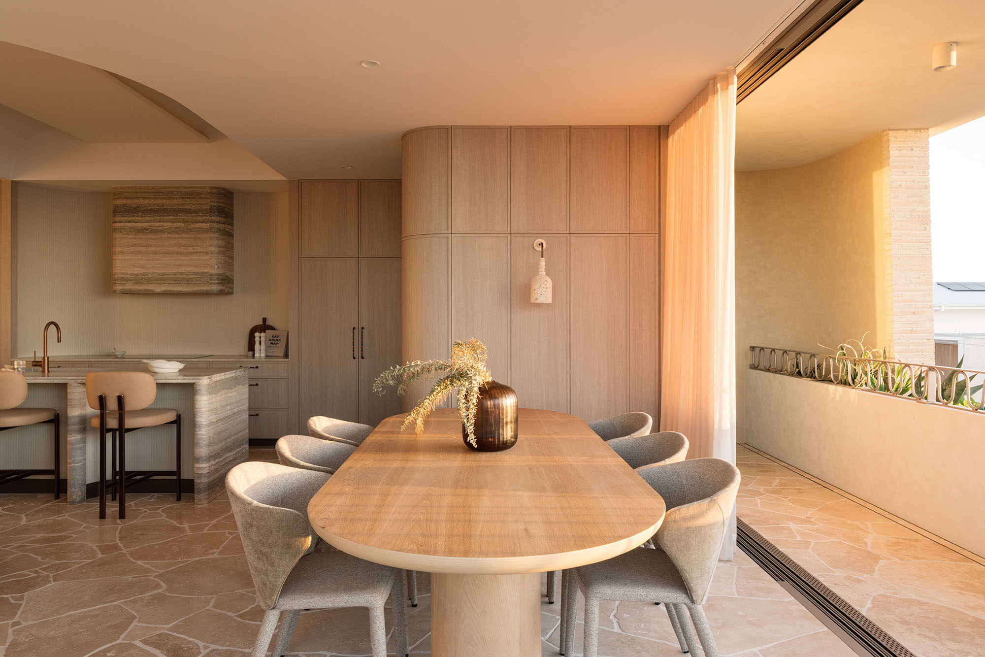 Modern dining area with wooden table and stylish chairs, bright natural light, and the Fossil Coral Arc Dome Wall Light.