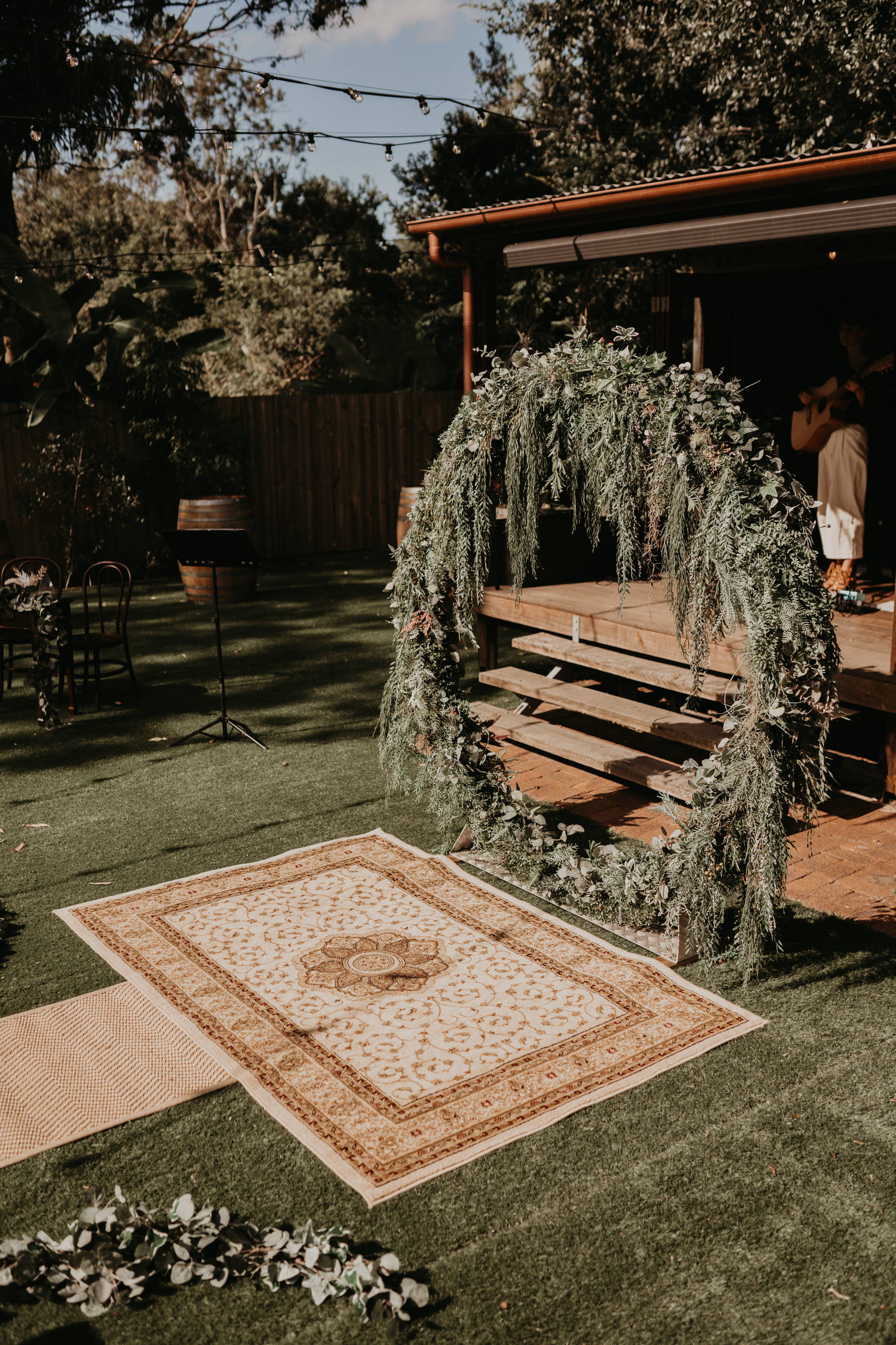 Garden wedding with rustic rug and circle shaped arbor gathered with leaves