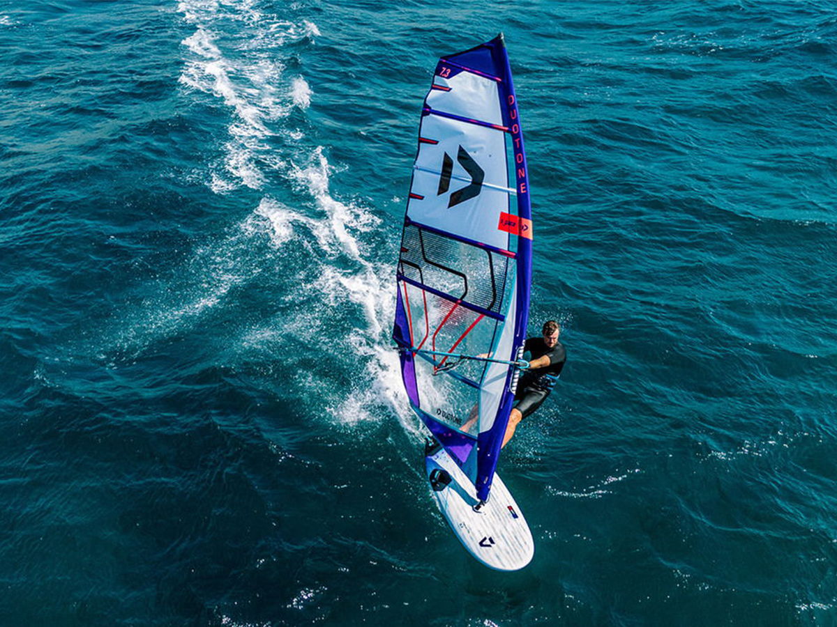 A person windsurfing on a blue ocean with white waves.