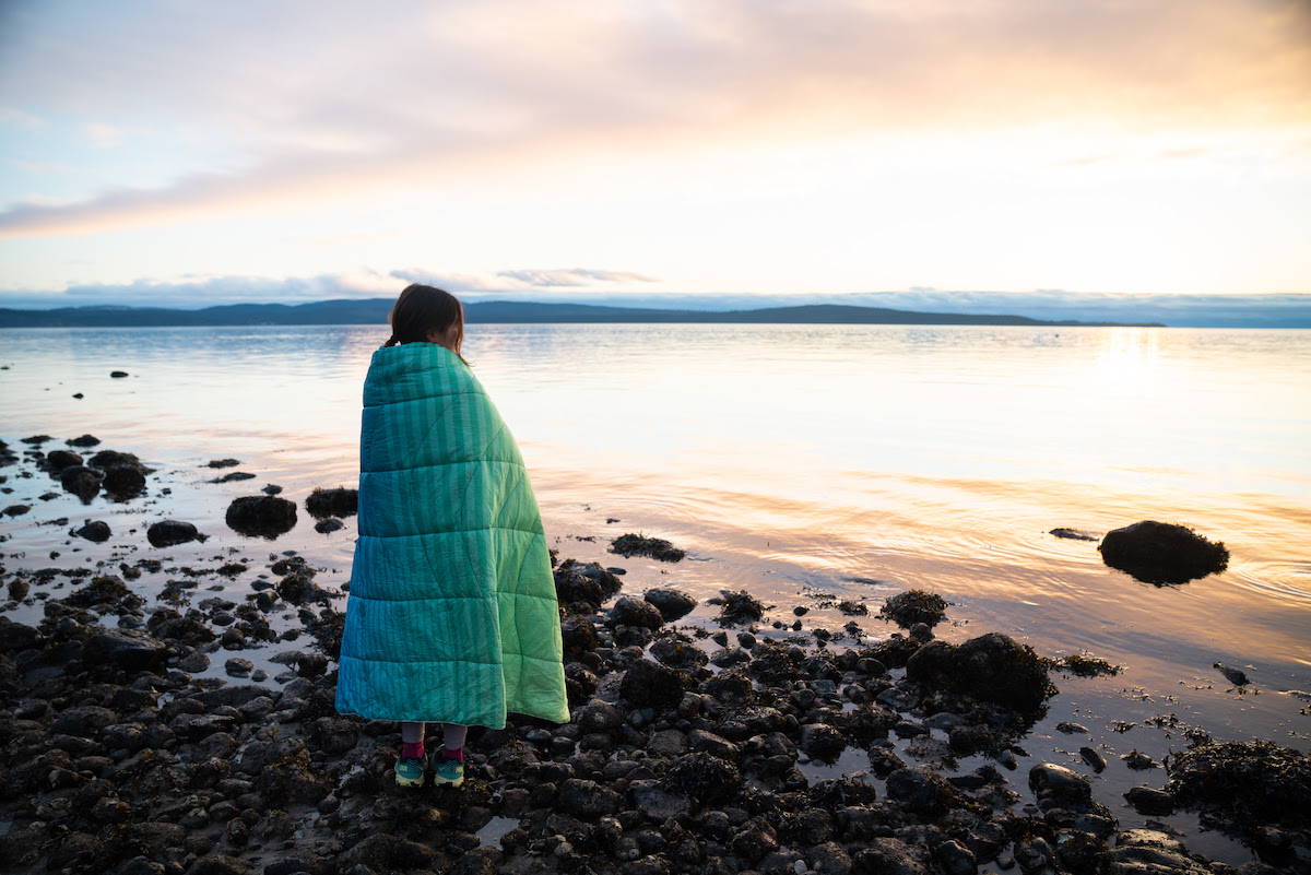 Woman Wrapped in NanoLoft Puffy Blanket Overlooking Lake
