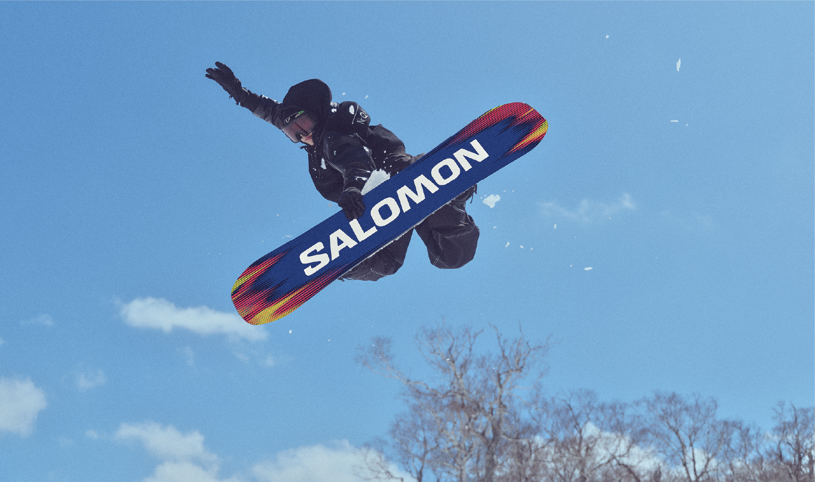 Snowboarder performing a jump against a clear blue sky.