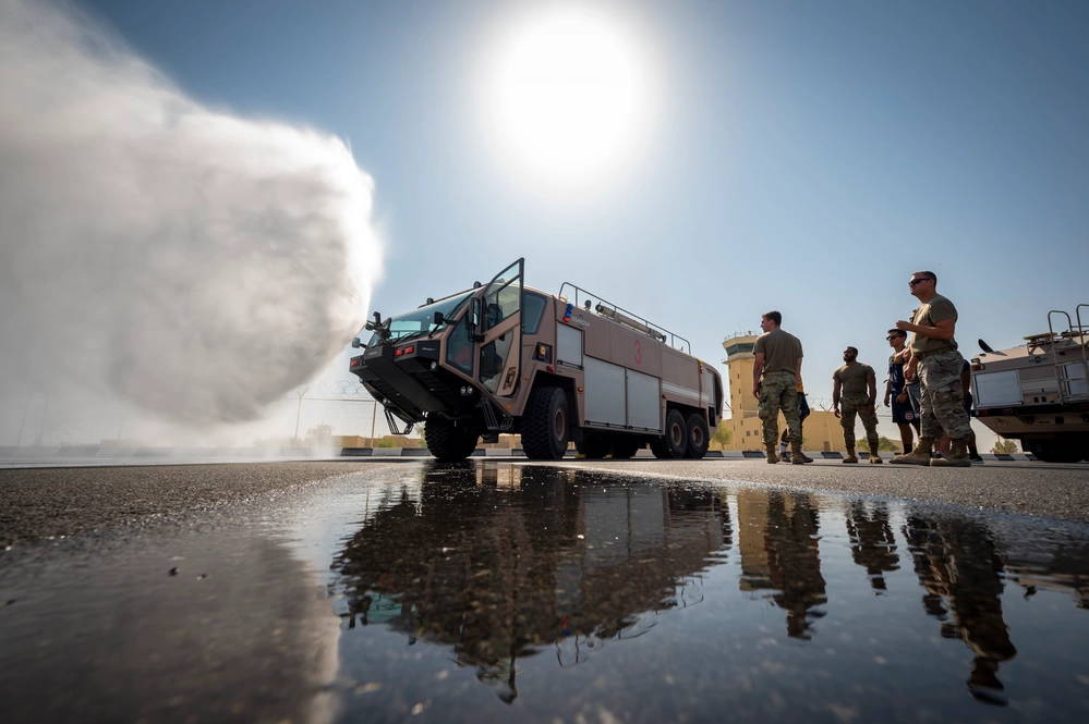 U.S. Air Force Airmen watch an Oshkosh Striker fire engine capabilities display at Al Udeid Air Base, Qatar, Nov. 27, 2021. The Striker fire engines are designed with a “snozzle” that is capable of penetrating an aircraft’s fuselage and extinguishing fires in the cargo or cabin areas. (U.S. Air Force photo by Senior Airman Noah D. Coger)