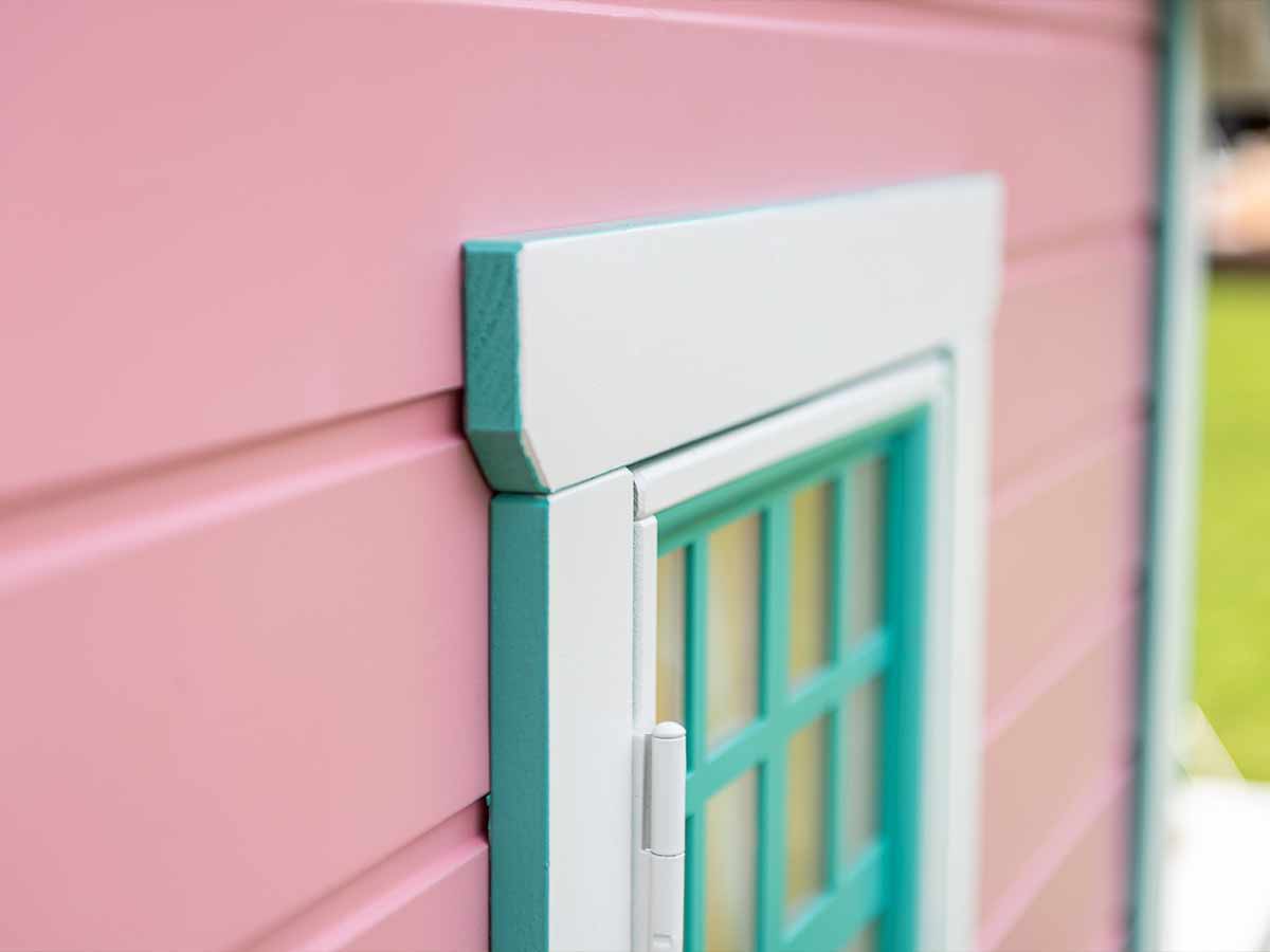Closeup of pink custom playhouse window corner with blue and white rims by WholeWoodPlayhouses