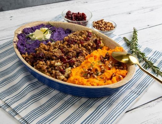 Colorful layered dish with purple, orange, and grainy toppings, garnished with herbs.