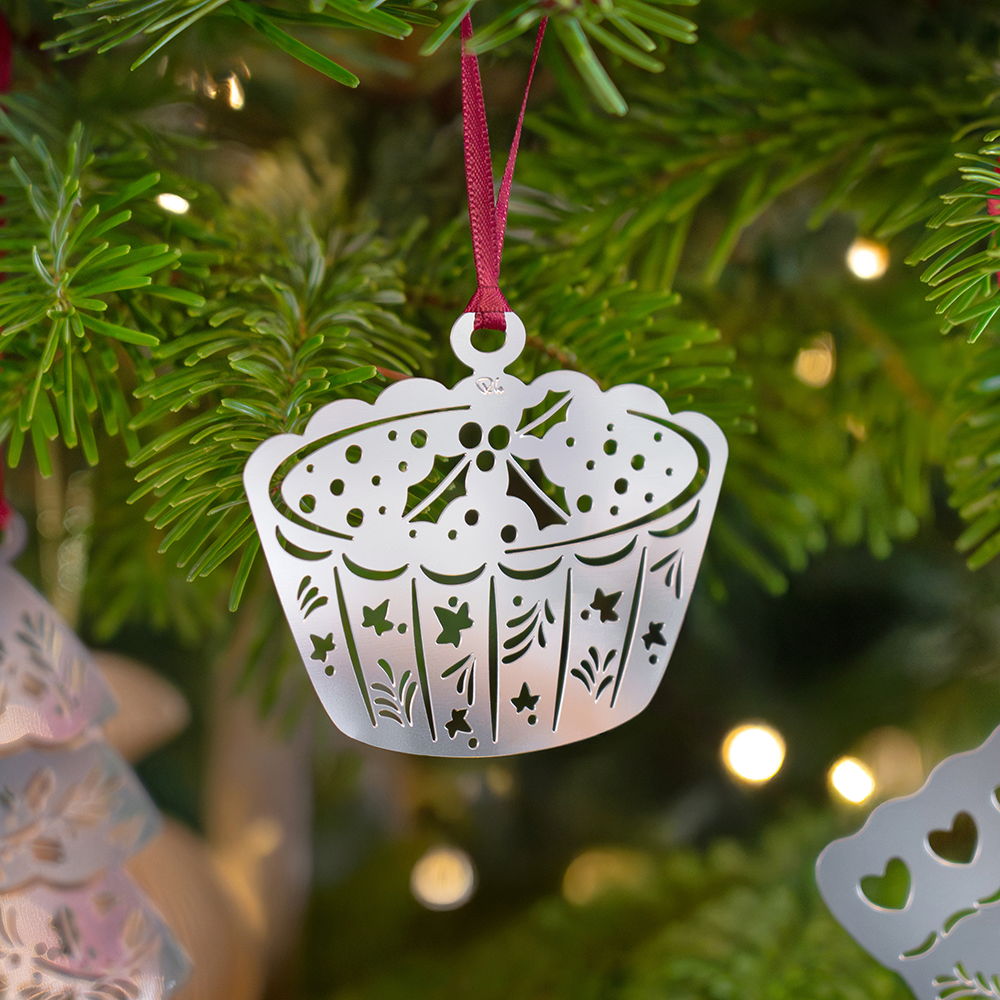 A decorative mince pie ornament hanging on a Christmas tree.