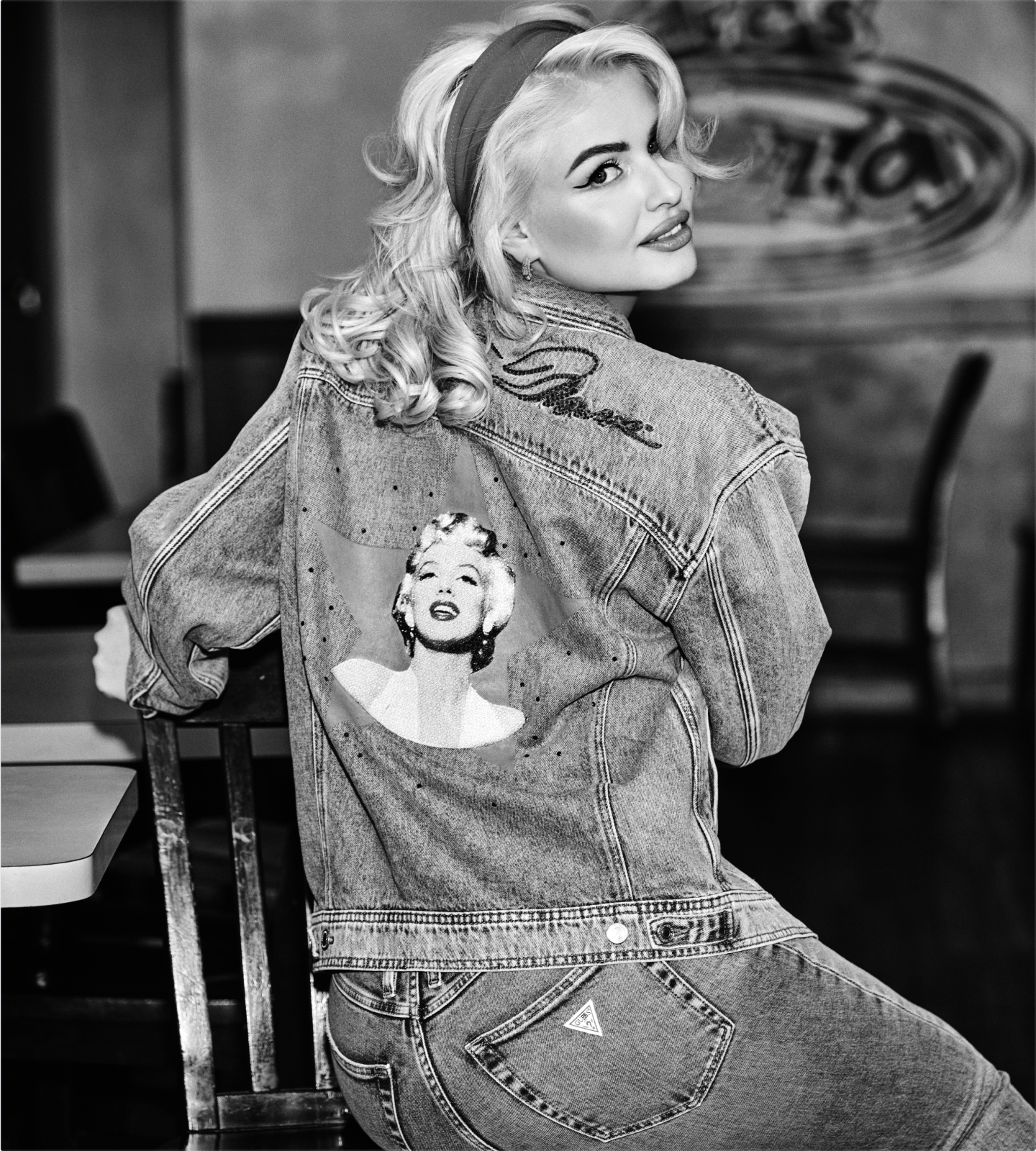 Woman in denim jacket with Marilyn Monroe graphic, smiling over her shoulder.