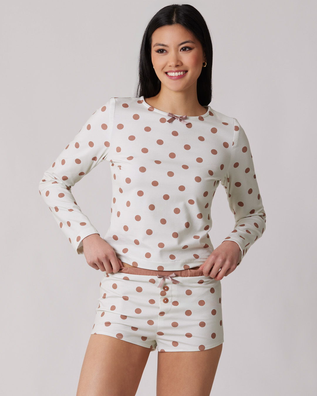 Smiling woman in patterned loungewear top and shorts, posing against a neutral background.