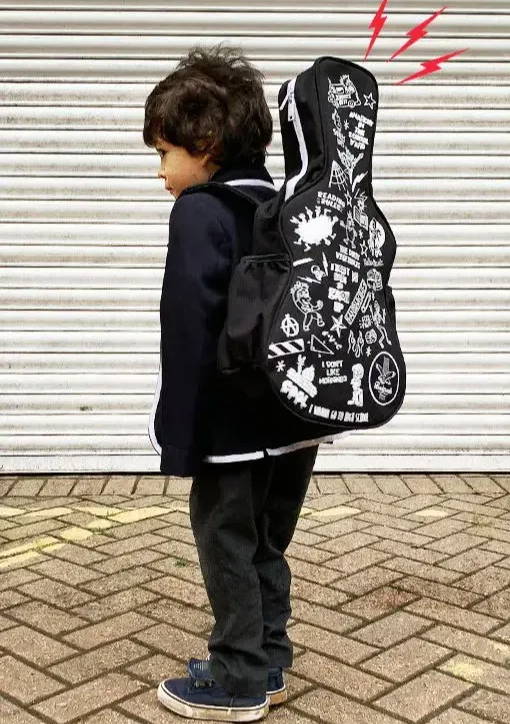 Young boy wearing a black outfit and black guitar shaped backpack