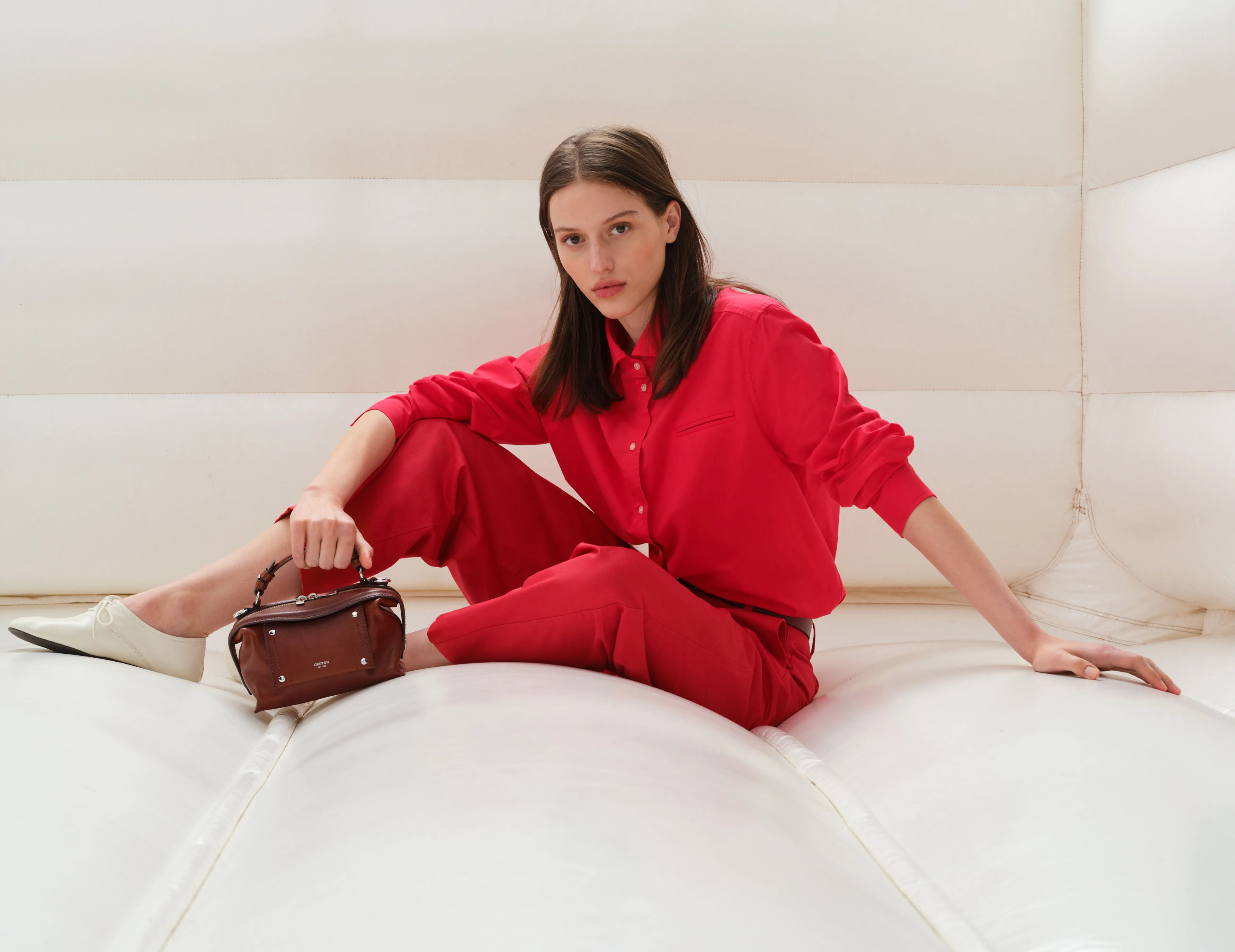Model in red outfit sitting in a white inflatable space.
