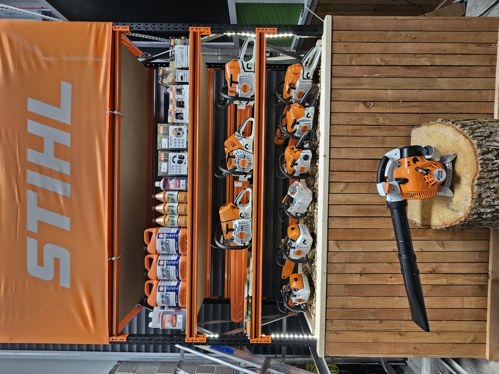 Stihl chainsaws and supplies displayed on wooden stand at trade show.