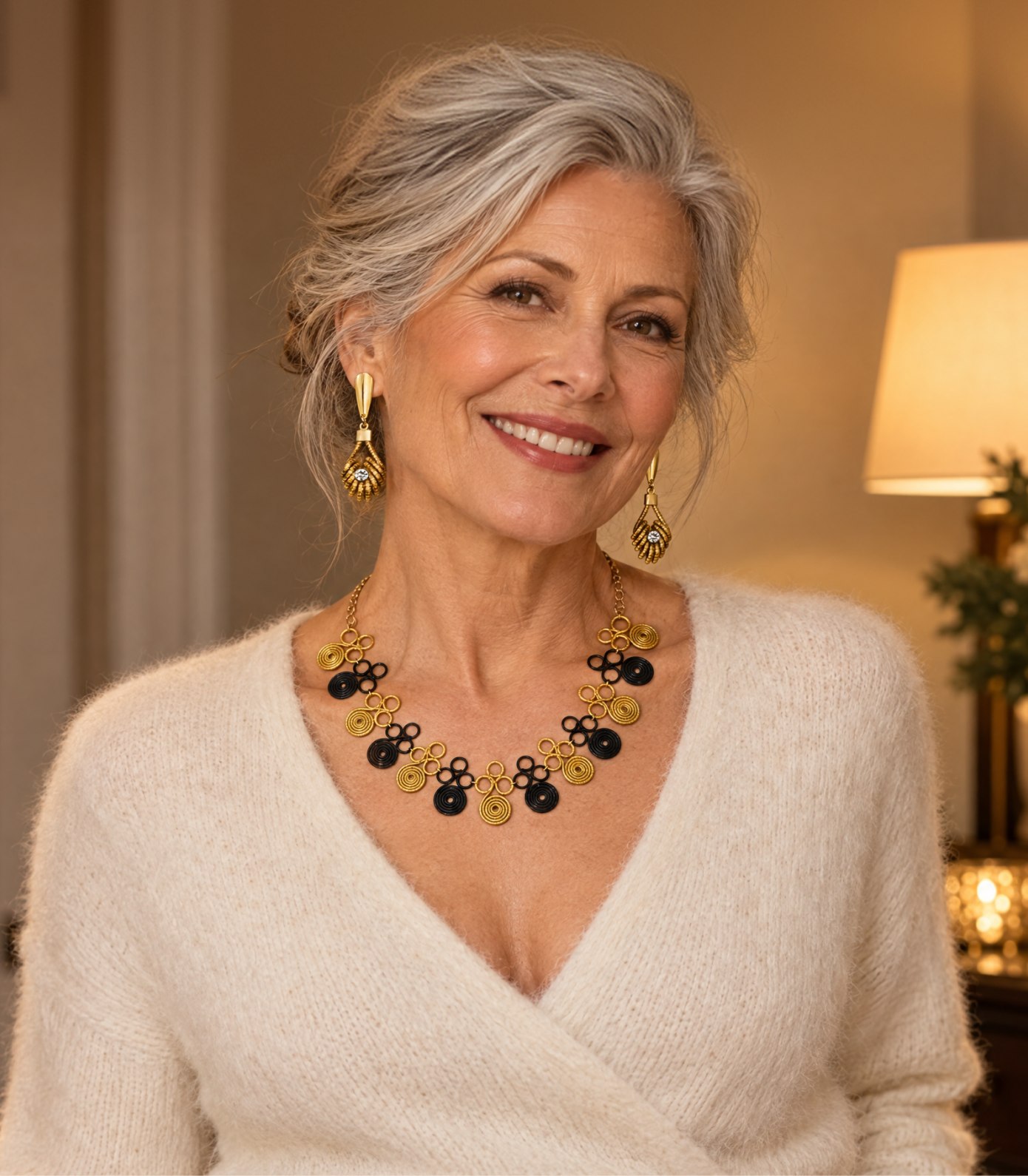 Woman in a cream sweater wearing golden grass spiral earrings and a red and gold woven necklace