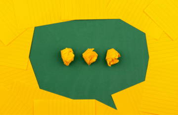 Three yellow paper crumples inside a green speech bubble on a yellow background.