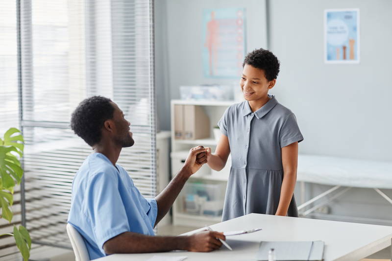 A smiling girl bumping fists with her doctor after an appointment about her allergies
