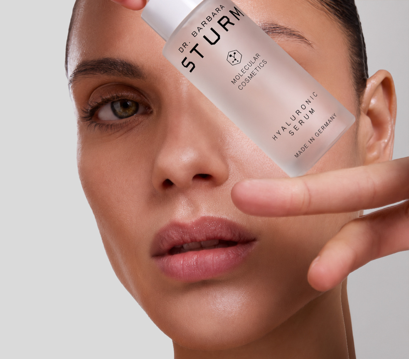 Woman holding a skincare product near her face.
