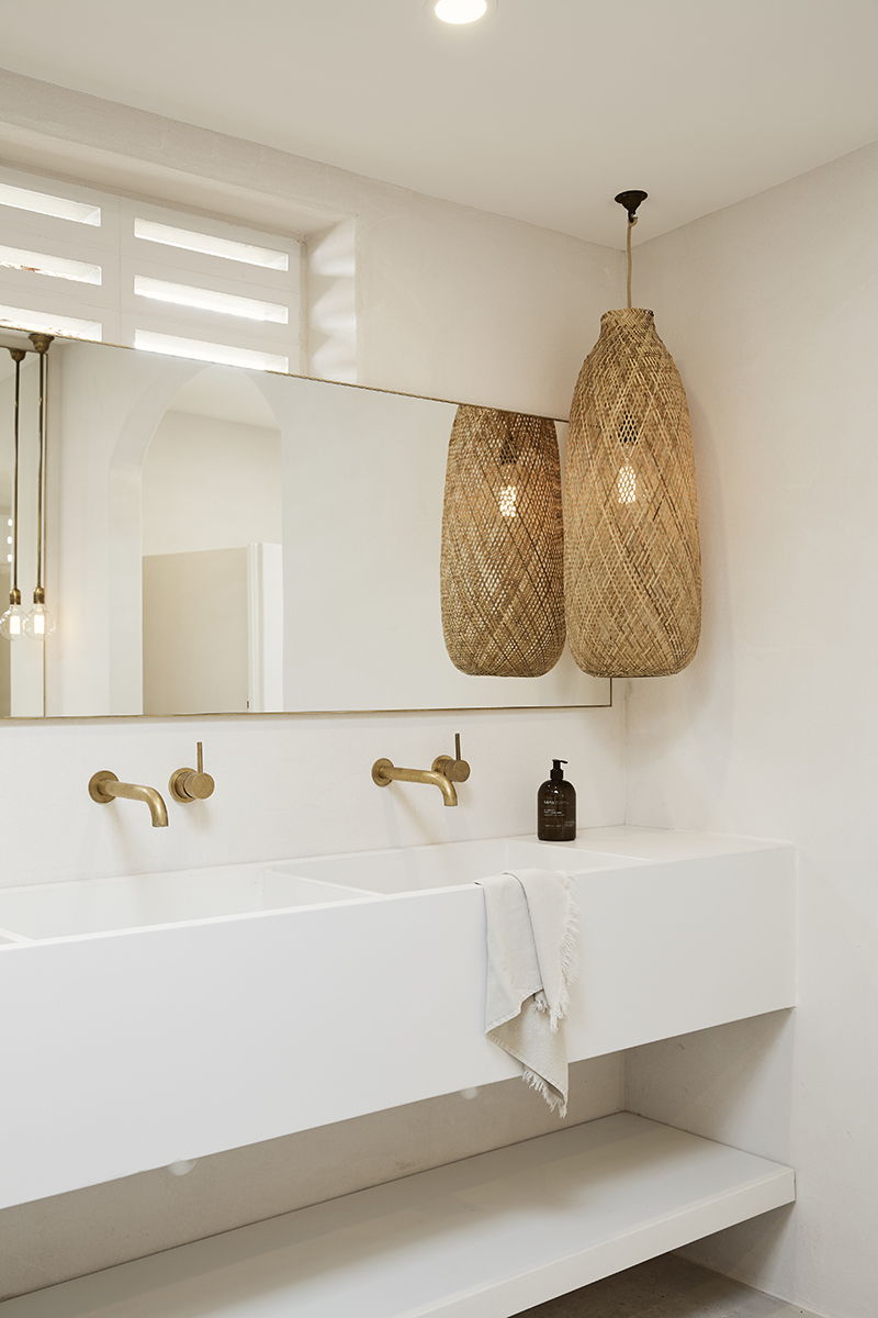 Modern bathroom with double sink, woven pendant lights, and large mirror.