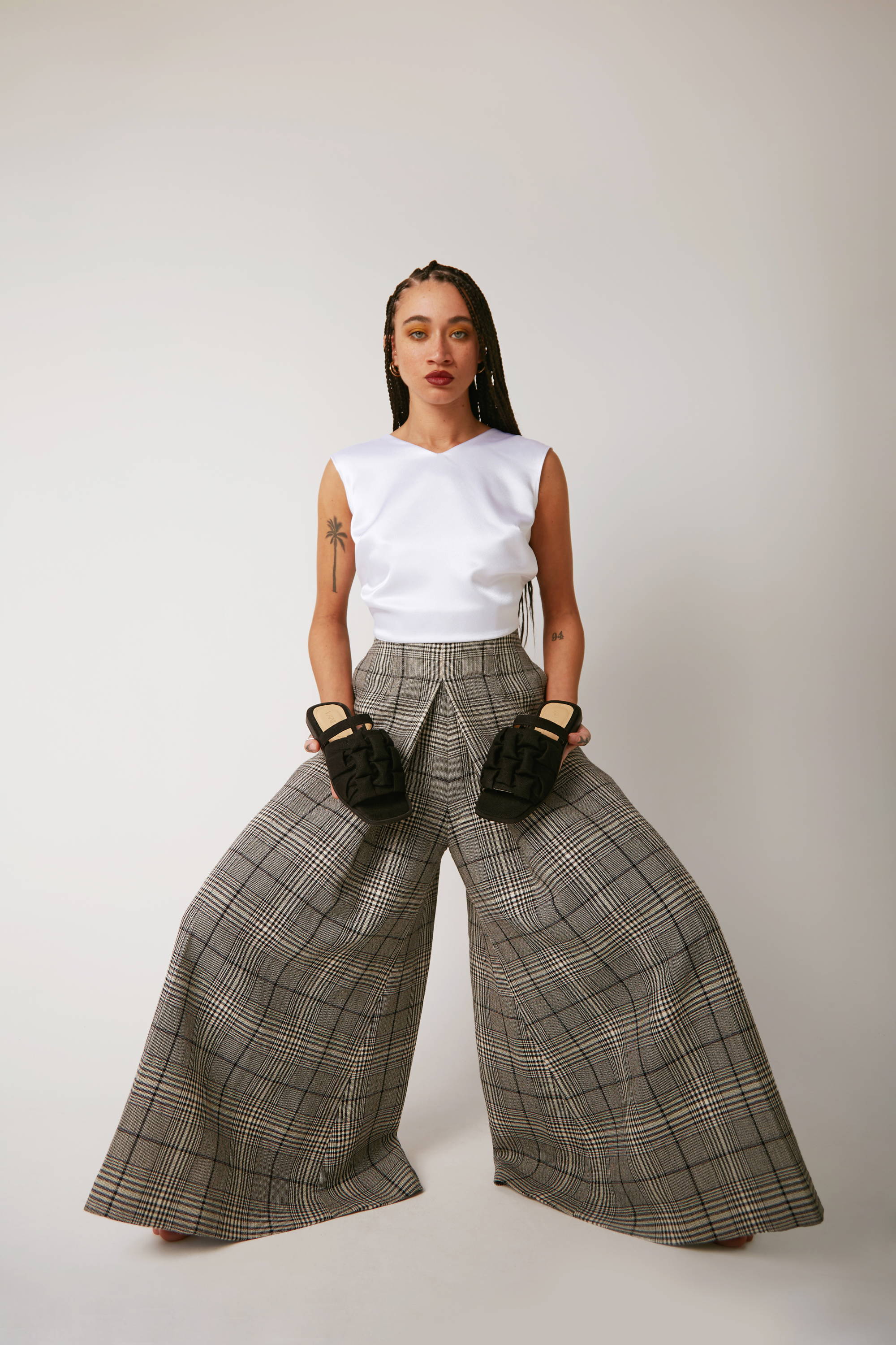 Vandrelaar vegan Simone sandal in black linen styled on model with wide legged checkered wool trousers and a satin white top