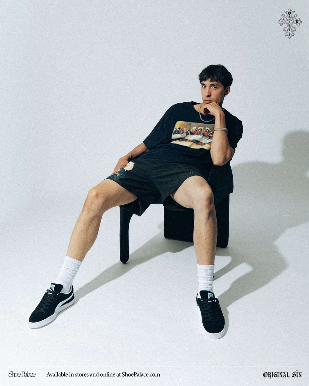 Young man sitting on a chair, wearing casual clothes and sneakers.