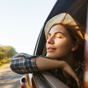 Woman enjoying a breeze while leaning out of a car window.