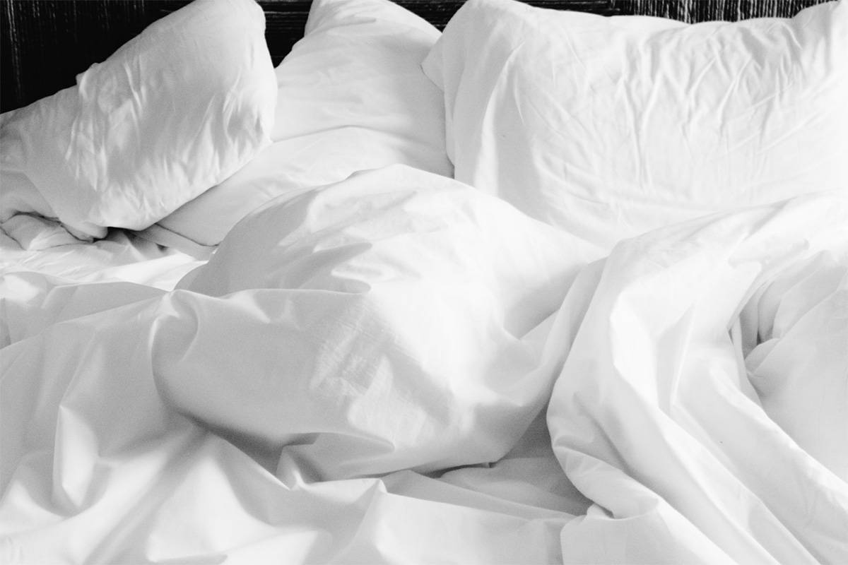 An image of a bed with crumpled white sheets