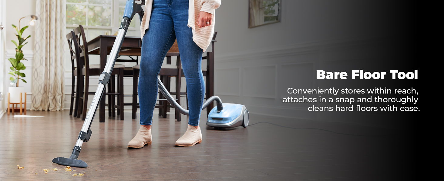 Person using a vacuum cleaner with a bare floor tool on wooden flooring.