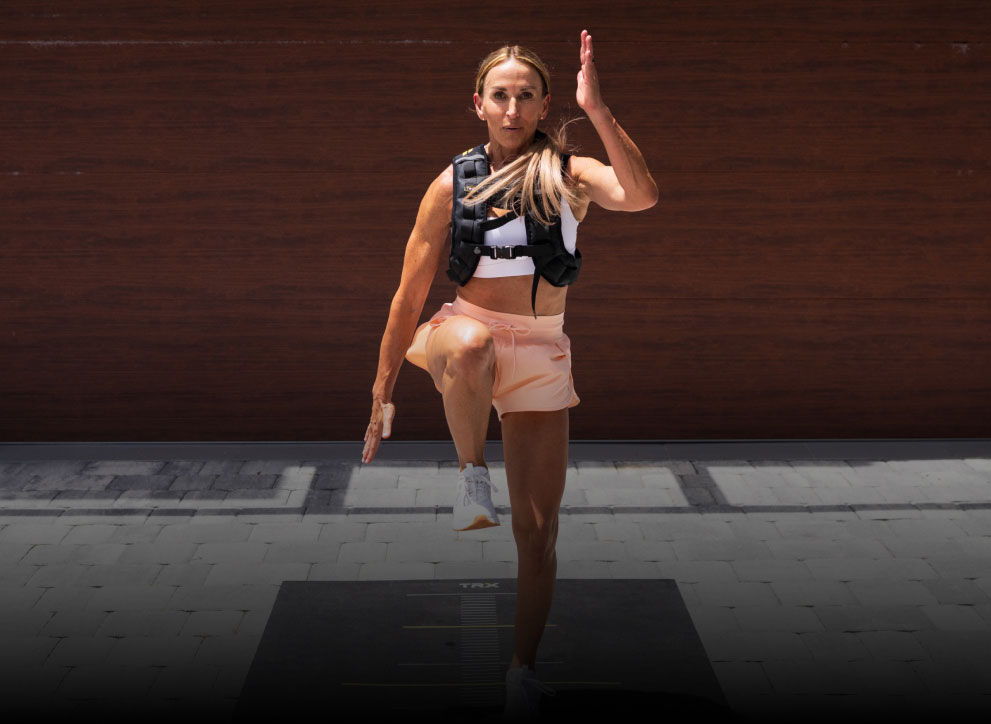 Person exercising outdoors, lifting one leg and arm, wearing workout gear.