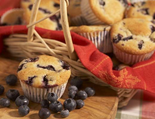 A basket of blueberry muffins with fresh blueberries.