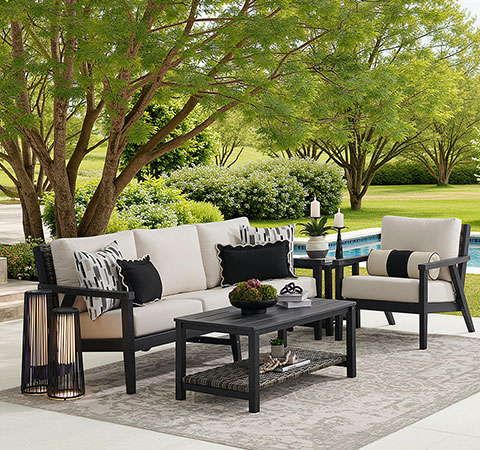 Outdoor seating area with a sofa, chairs, table, and greenery.