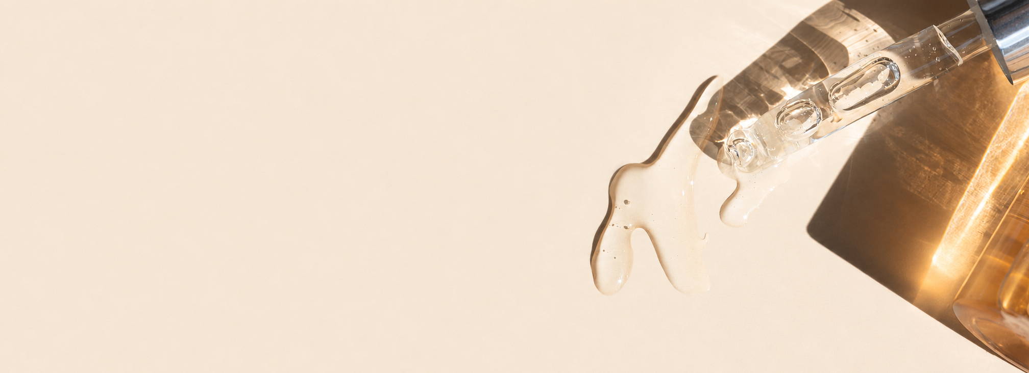 Glass bottle pouring liquid against a soft, neutral background.