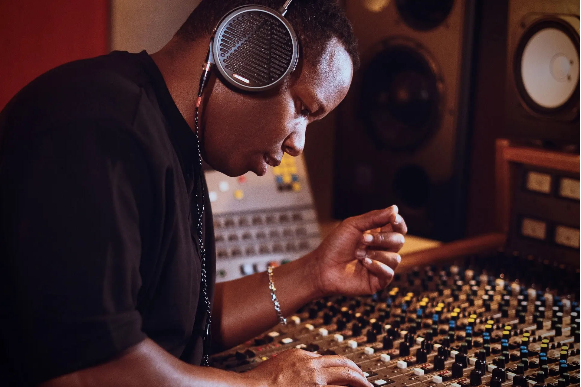 Person wearing MM-100 headphones, adjusting audio equipment in a recording studio.