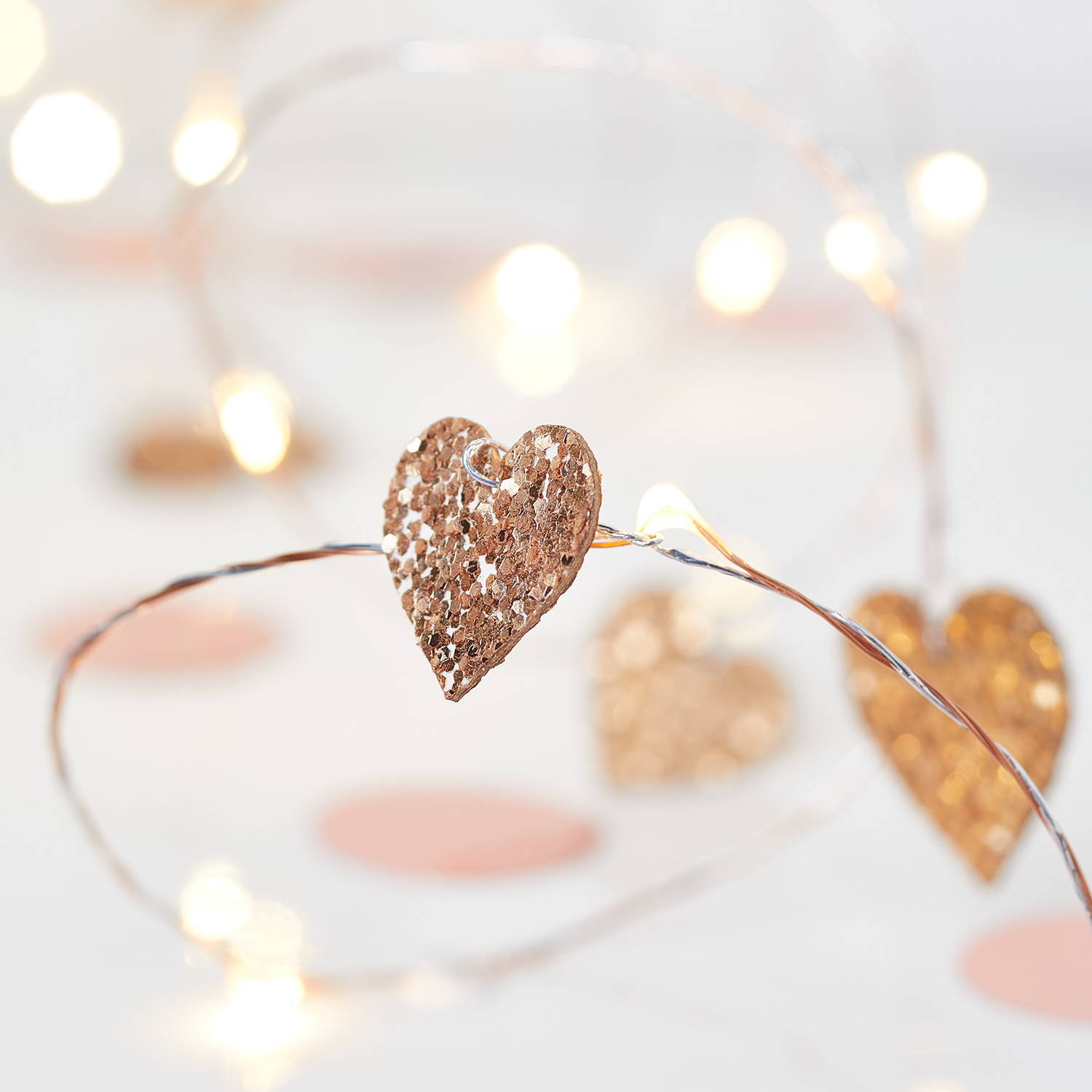 Glittery pink heart micro lights on a white surface.