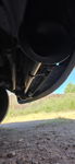 Low-angle view of black train horn trumpet mounted on chrome rod under vehicle