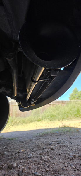 Low-angle view of black train horn trumpet mounted on chrome rod under vehicle