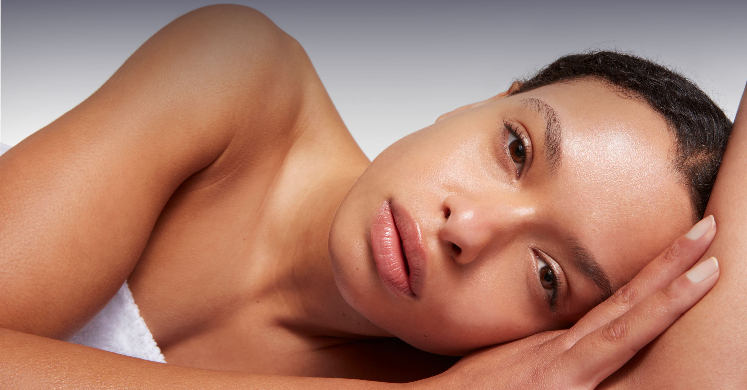A woman resting her head on her arm, looking contemplative.