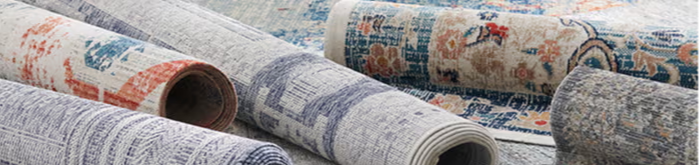 Rolled fabrics with various patterns and textures on a flat surface.