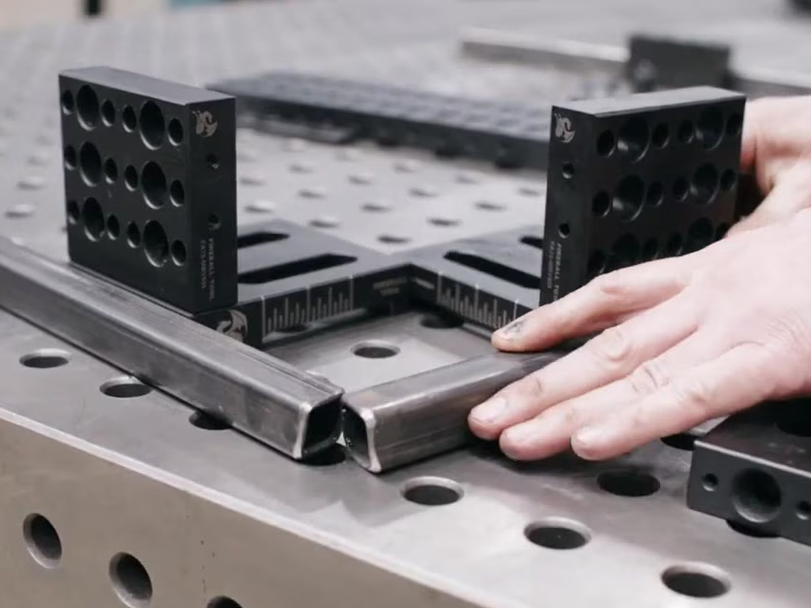 Two riser block fixtures holding a tube frame square at the corner