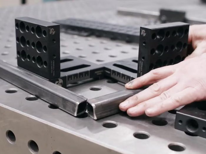 Two riser block fixtures holding a tube frame square at the corner