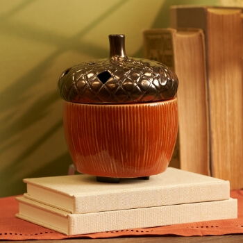 A decorative acorn-shaped container on stacked books.