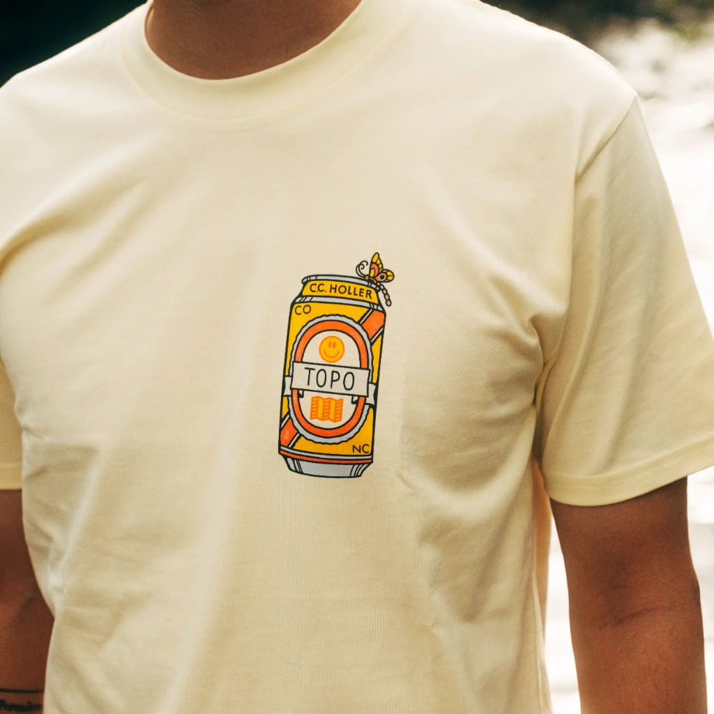 Person wearing a light yellow t-shirt with a colorful can graphic.