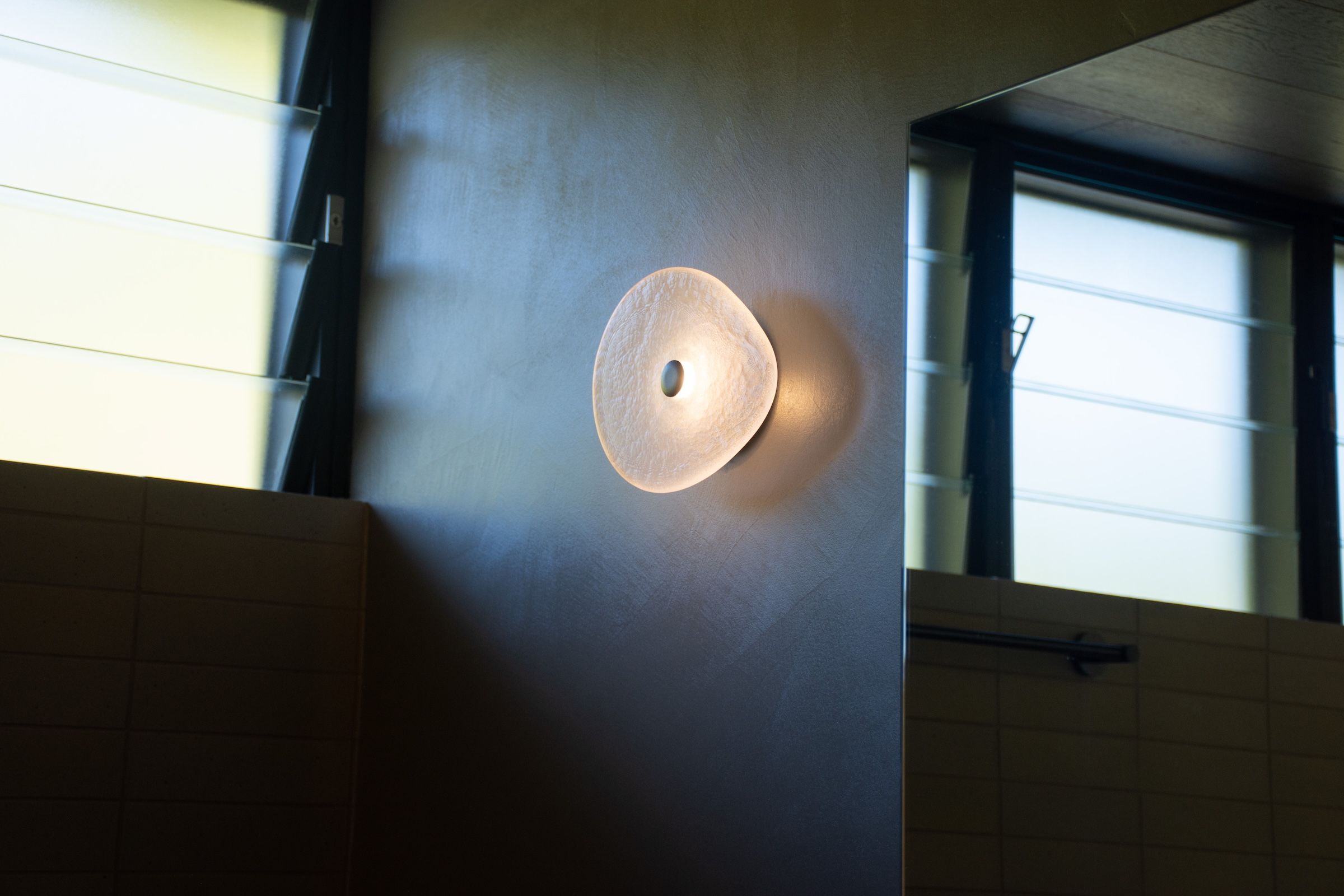 A organic glass wall light mounted near windows.