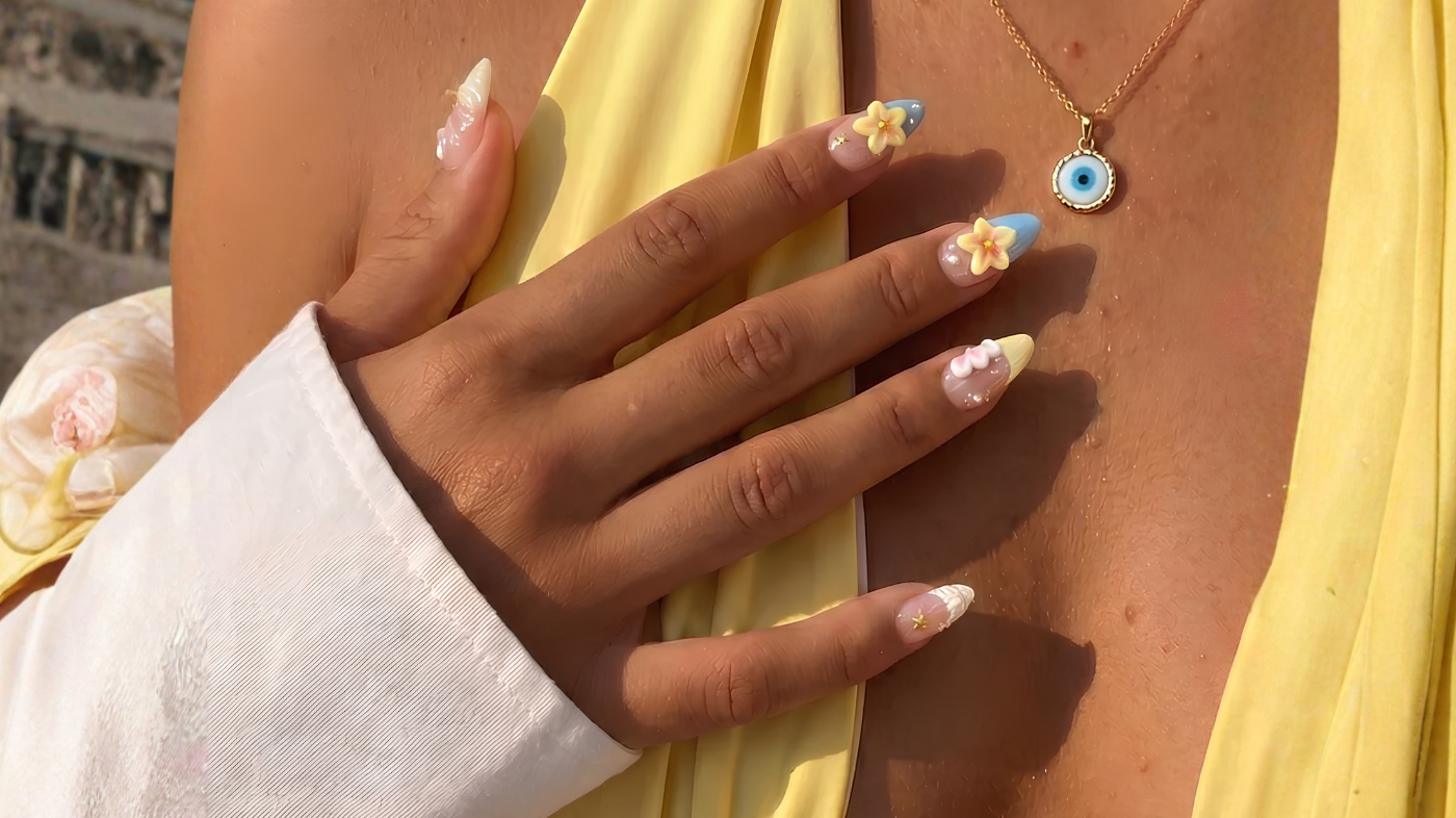 Hand wearing EyeCandys Shell Yeah press-on nails with floral summer nail design in soft pastel aesthetic style