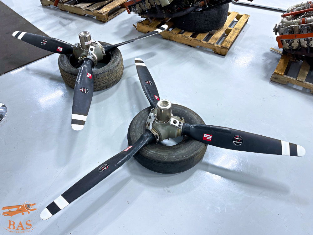 Two aircraft propellers on tires, placed on a workshop floor.